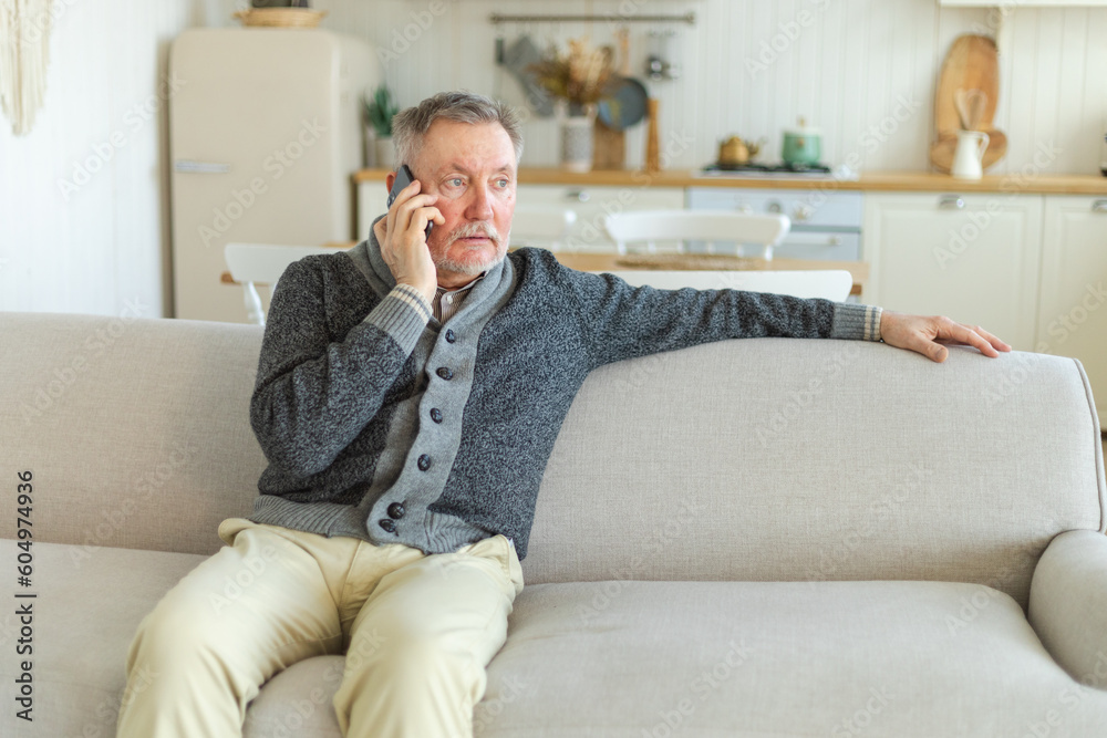 Happy middle aged senior man talking on smartphone with family friends. Older mature grandfather with cell phone talking with grown up children, resting at home. Older generation modern tech usage Happy middle aged senior man talking on smartphone with family friends. Older mature grandfather with cell phone talking with grown up children, resting at home. Older generation modern tech usage