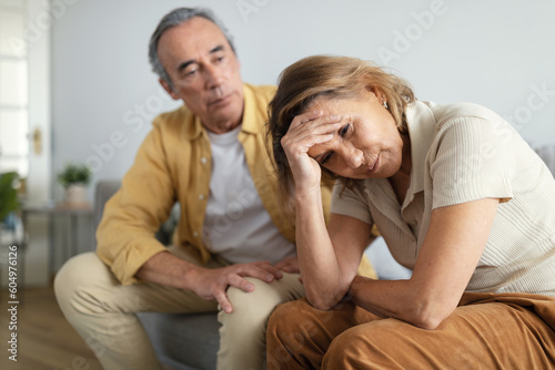 Couple misunderstanding. Depressed senior wife sitting upset after argue with husband, woman touching head