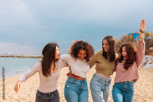Four diverse best girl friends jumping together on beach.