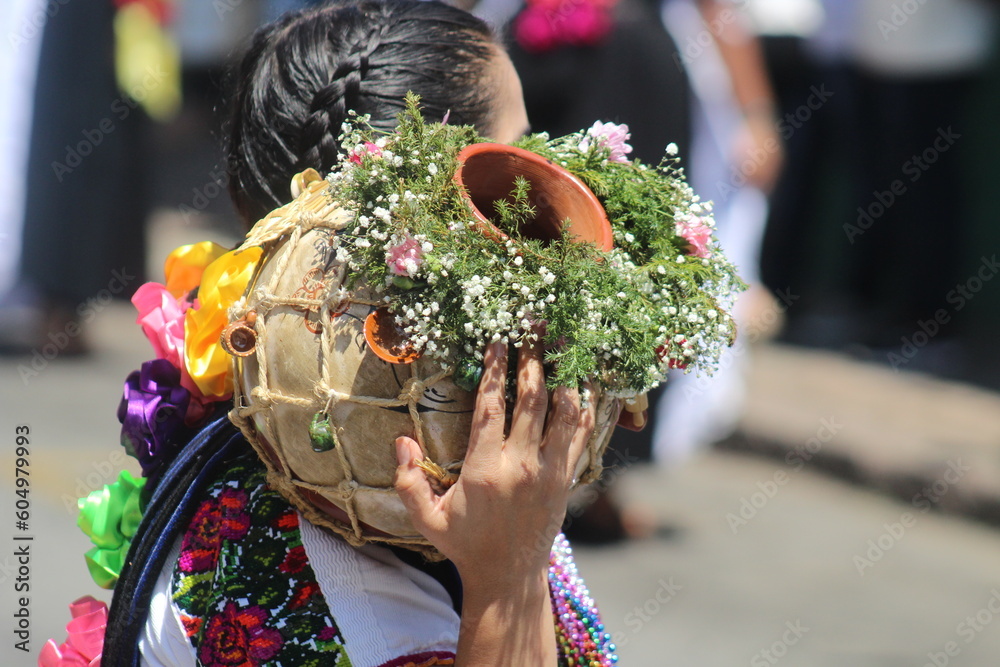 indigenous woman carrying a pitcher decorated with field flowers