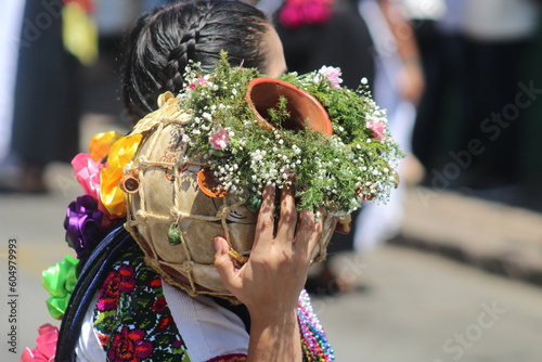 Obraz na płótnie indigenous woman carrying a pitcher decorated with field flowers w salonie