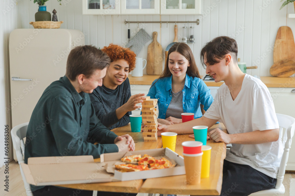 Home party. Friends spending time together playing in board game crash wooden tower at home. Happy diverse group having fun together indoor. Mixed race young buddies best friends enjoying weekend