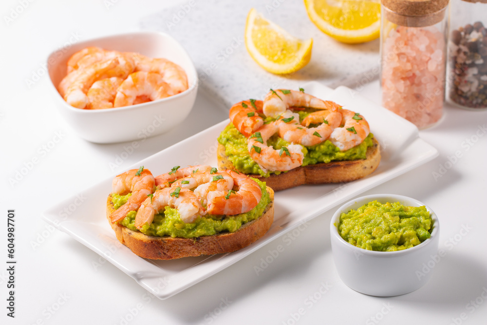 Appetizer toasted bruschetta with mashed avocado and shrimps on background. Healthy food concept with prawns.