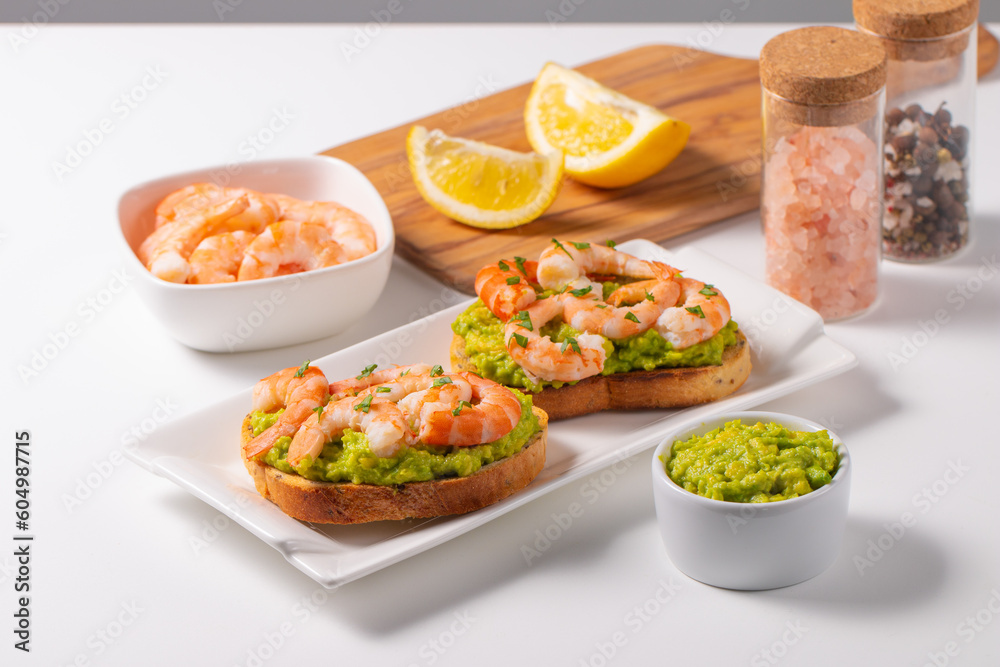 Appetizer toasted bruschetta with mashed avocado and shrimps on background. Healthy food concept with prawns.