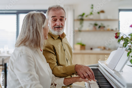 Beautiful eldery couple playing a piano at home photo