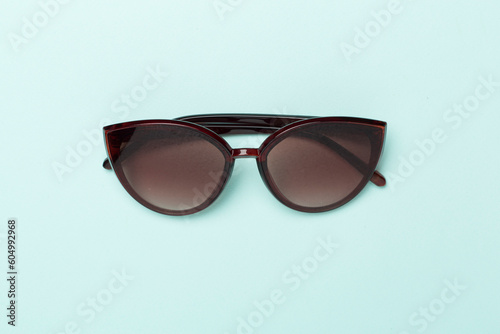 Sunglasses on color background, top view.