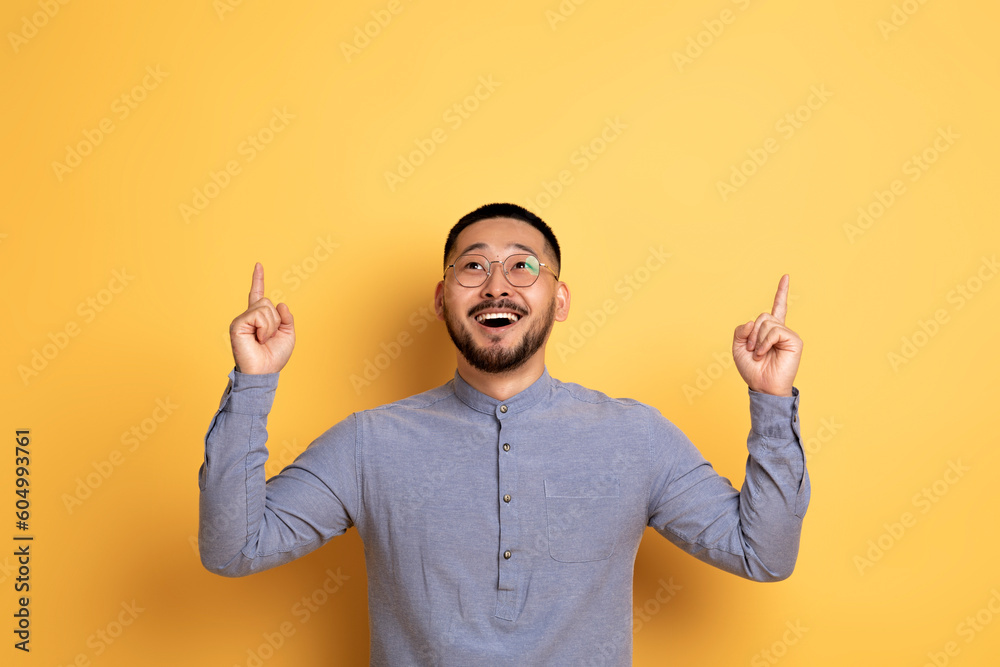 Place For Ad. Excited young asian man pointing up at copy space Place For Ad. Excited young asian man pointing up at copy space