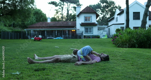 Parent and baby lying on grass outside