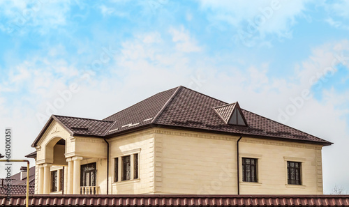 Roofs of houses made of metal slate against the sky. Modern metal roof. Metal tile and metal tile.