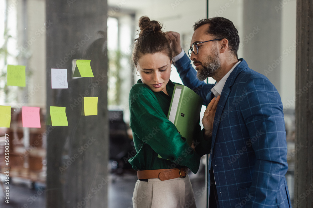 © Halfpoint - Mature man abusing his younger colleague, concept of harassment at workplace.