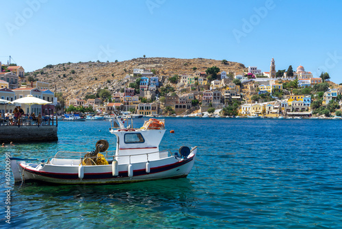 Fishing or shrimp boat, shrimping boats or shrimpers with houses of Greek mountainous Symi Island, Dodecanese island chain. Harbor town of Symi and adjacent upper town Ano Symi