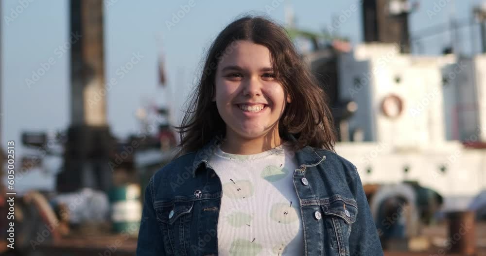 The moment of a young girl at the seaside, looking at the camera with surprise and then waving her hand in a cute manner The moment of a young girl at the seaside, looking at the camera with surprise and then waving her hand in a cute manner