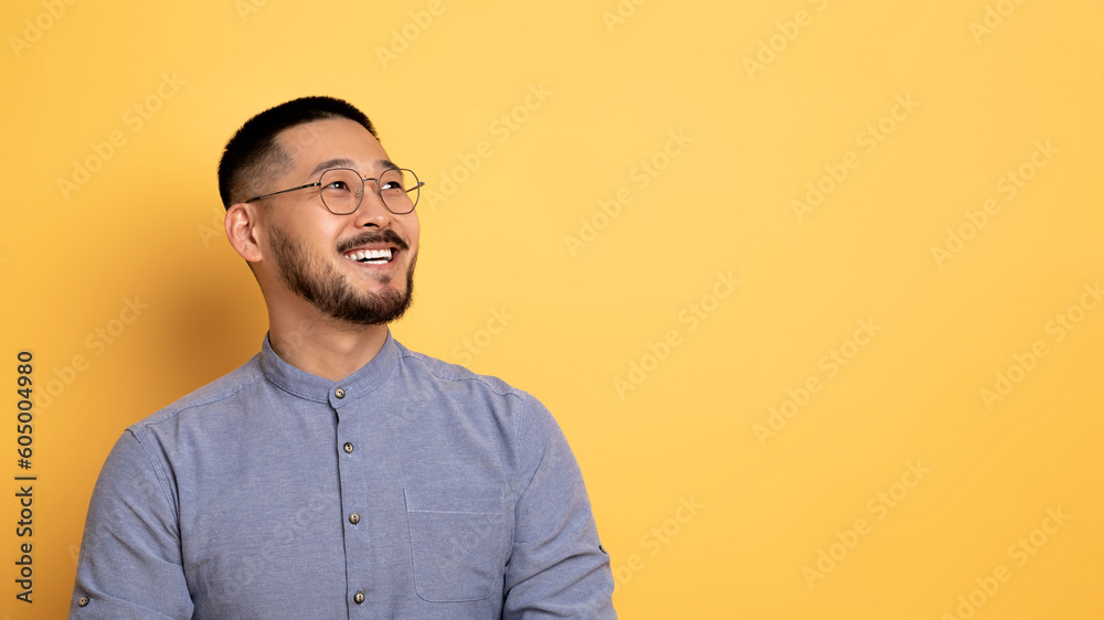 Obraz premium Nice Offer. Smiling Asian Man Looking Aside At Copy Space With Interest