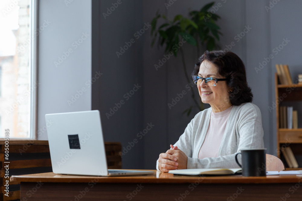 Happy middle aged senior woman sit with laptop talk on video call with friends family. Laughing mature old senior grandmother having fun talking speaking with grown up children online Happy middle aged senior woman sit with laptop talk on video call with friends family. Laughing mature old senior grandmother having fun talking speaking with grown up children online