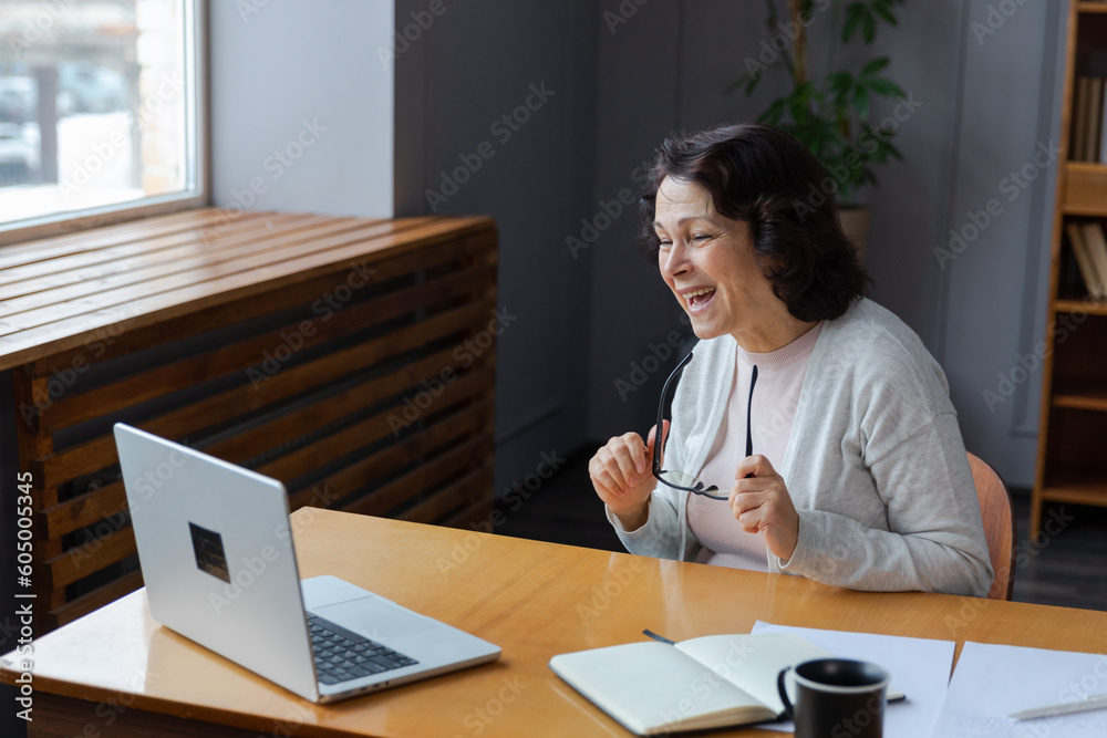 Happy middle aged senior woman sit with laptop talk on video call with friends family. Laughing mature old senior grandmother having fun talking speaking with grown up children online Happy middle aged senior woman sit with laptop talk on video call with friends family. Laughing mature old senior grandmother having fun talking speaking with grown up children online