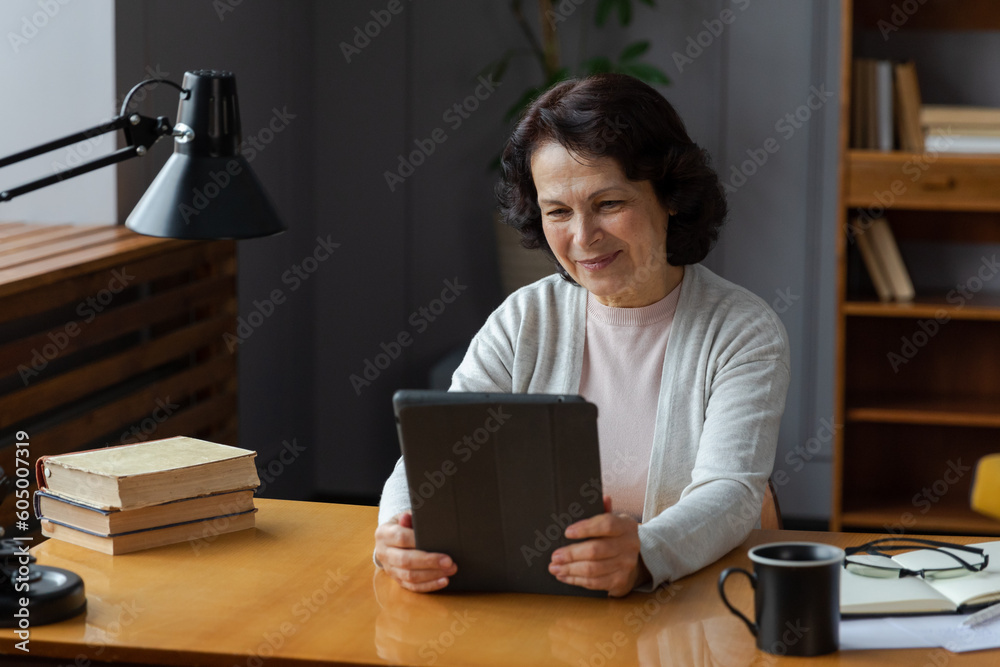 Happy middle aged senior woman holding tablet talk on video call with friends family. Laughing mature old senior grandmother having fun talking speaking with grown up children online Happy middle aged senior woman holding tablet talk on video call with friends family. Laughing mature old senior grandmother having fun talking speaking with grown up children online