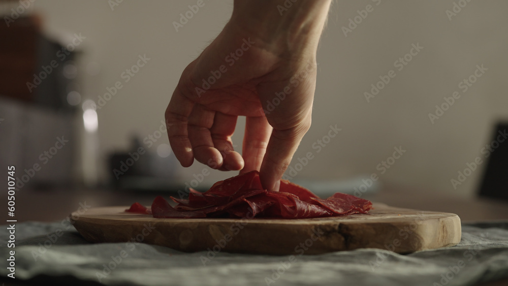 man takes slices of beef pastrami from olive wood board man takes slices of beef pastrami from olive wood board
