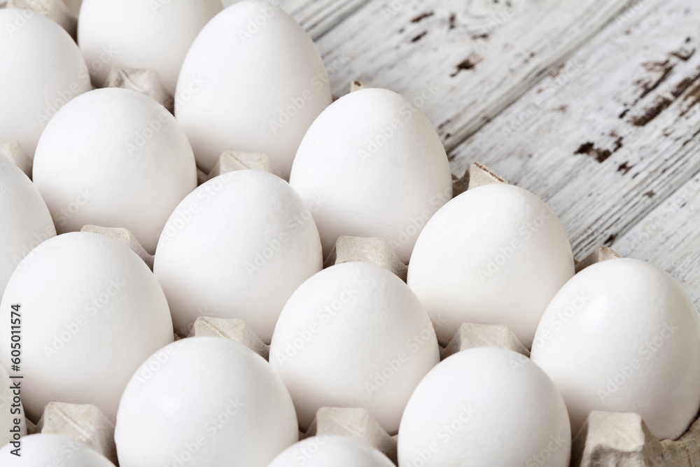 Close-up of Cardboard tray with white chicken eggs on wooden background Close-up of Cardboard tray with white chicken eggs on wooden background
