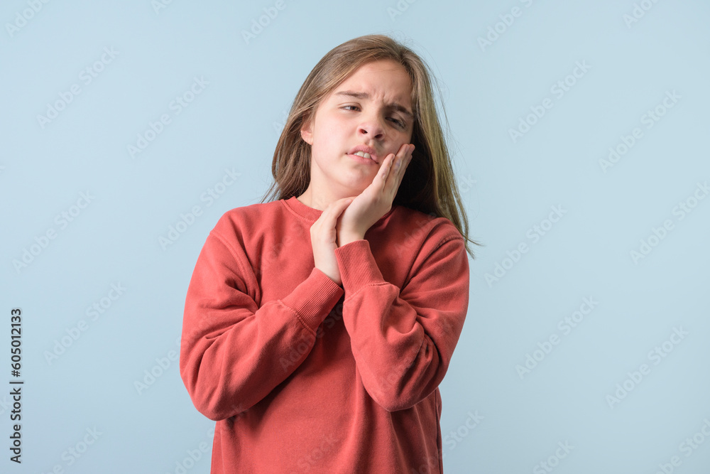 Young girl over light blue isolated background wearing red sweater touching mouth with hand with painful expression. Dentist Young girl over light blue isolated background wearing red sweater touching mouth with hand with painful expression. Dentist