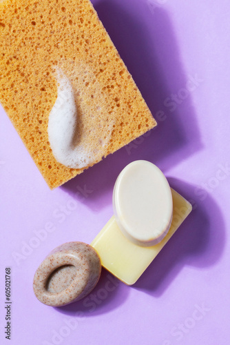 Obraz na płótnie Handmade soap with the addition of coffee and wild herbs and a sponge with foam on a purple background. w salonie