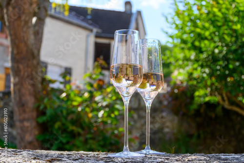 Tasting of premier cru sparkling rose wine with bubbles champagne with view on old houses of Hautvillers, where lived Benedictine monk how developed champagne wine, France.