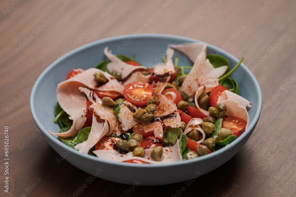 Salad with prosciutto cotto, cherry tomatoes and spinach in blue bowl Salad with prosciutto cotto, cherry tomatoes and spinach in blue bowl