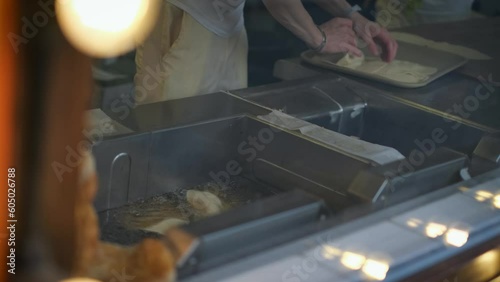 Unrecognizable chef fries chebureks and pies at a fast food point, close-up photo