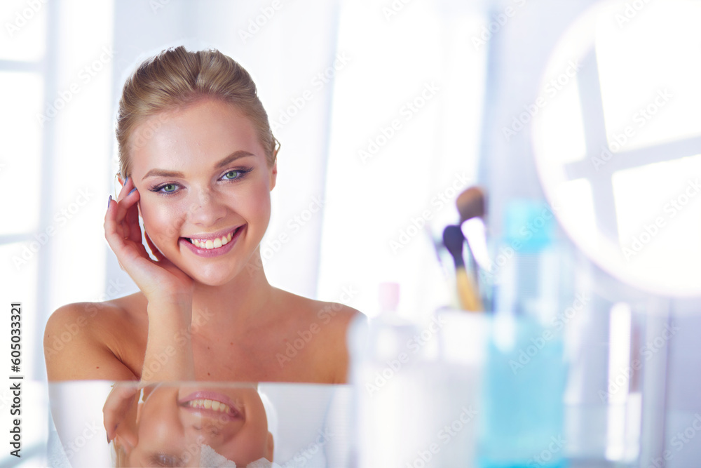 Young woman in bathrobe looking in bathroom mirror