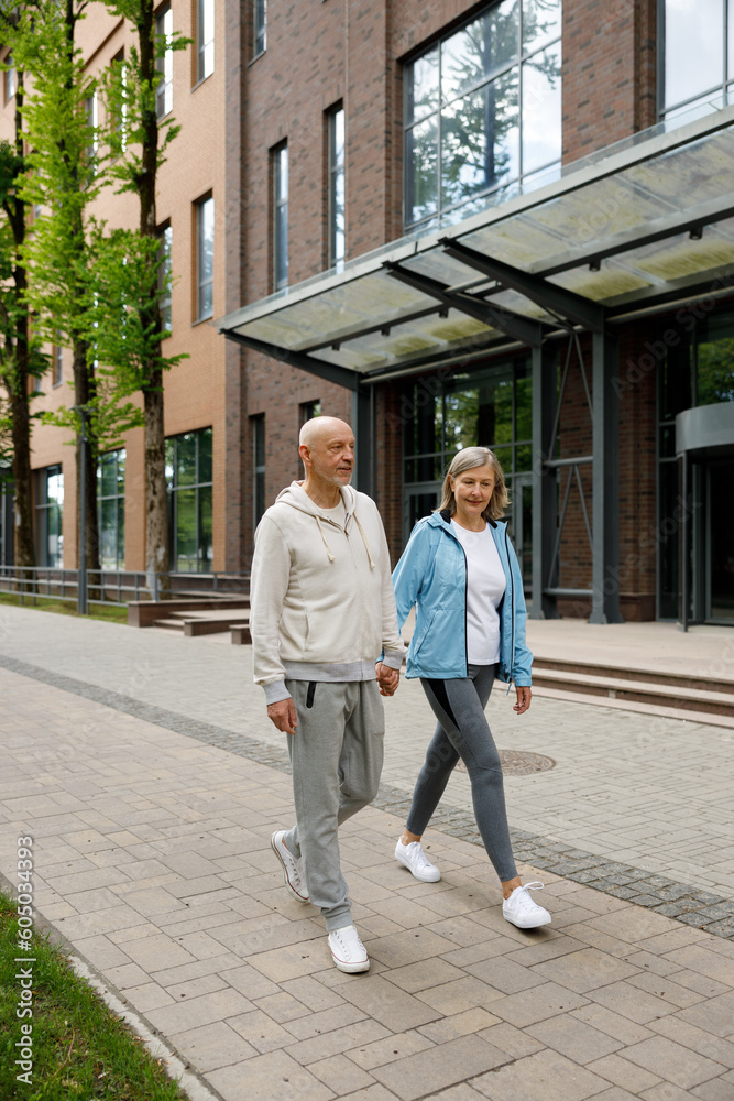 Matured Sporty Lovely Couple Is Walking After Running Holding the Bottle of Water. Sport and Communication Concept