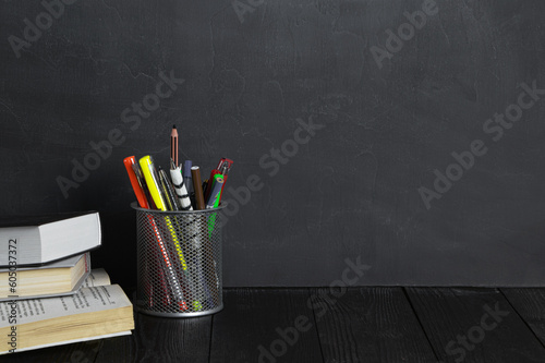 School and education concept.Copy space. Chalk board and old books. Pens and pencils in a bucket.Chalk rubbed out on blackboard. Chalkboard background