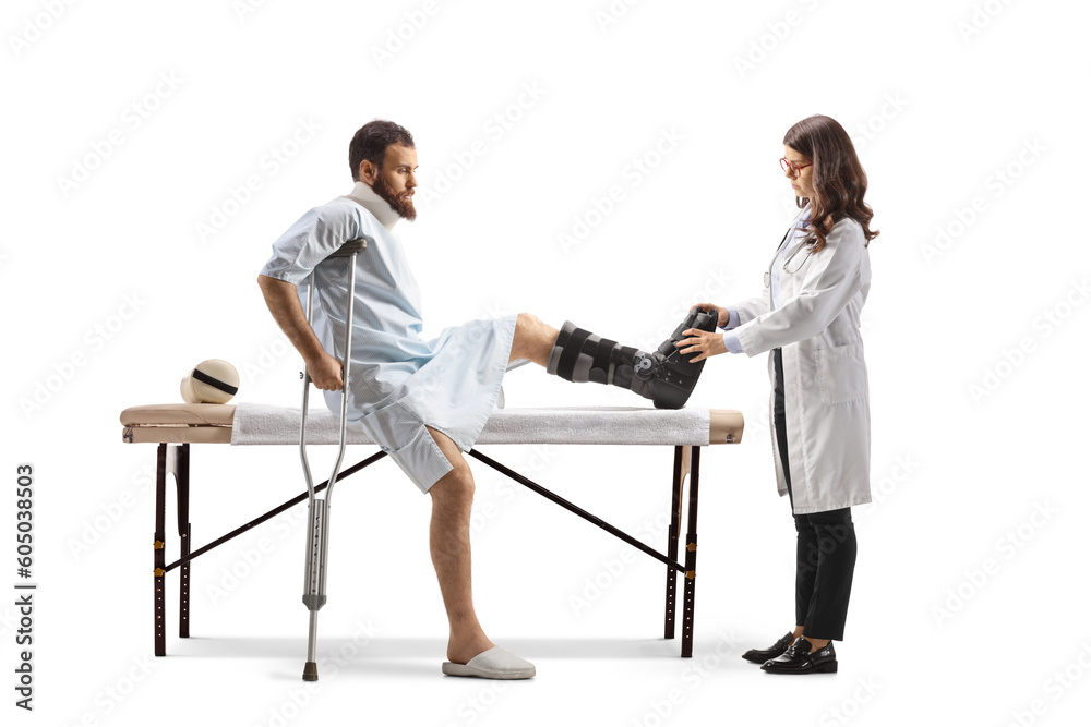 Obraz premium Female doctor putting on a walking brace to a male patient in a hospital gown