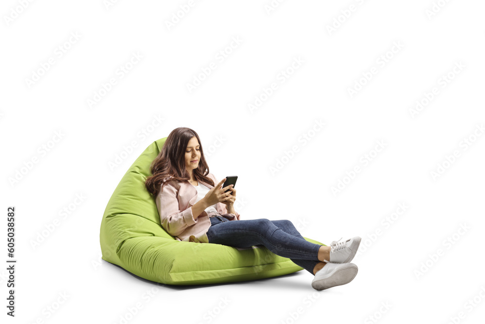 Young female seated on a bean bag smiling and looking at a smartphone