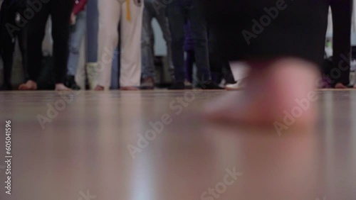 The feet of two men who are dancing capoeira in a gymnasium