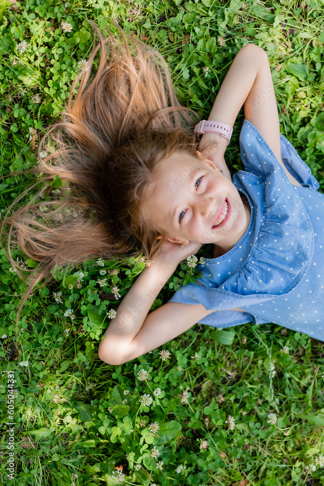 happy little girl lying on the green grass in summer top view happy little girl lying on the green grass in summer top view