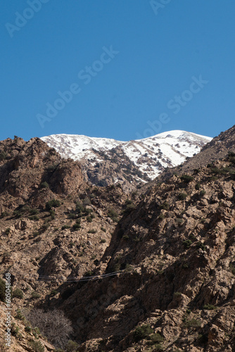 Peak of a snow mountain above the dirt mountains of the Ourika Valley in Morocco