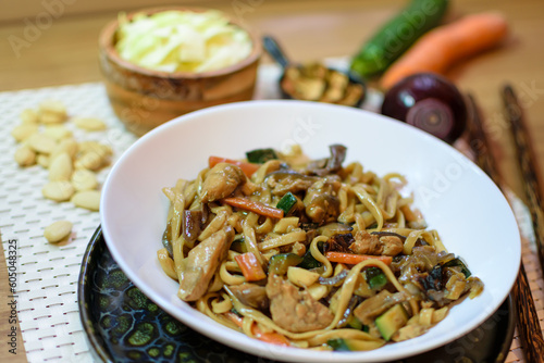 Rice noodles served with vegetables and meat in white bowl.