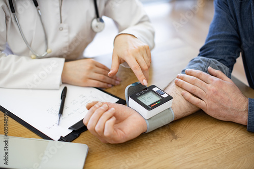 Billede på lærred Crop of male patient measuring blood pressure with modern electronic tonometer in medical centre