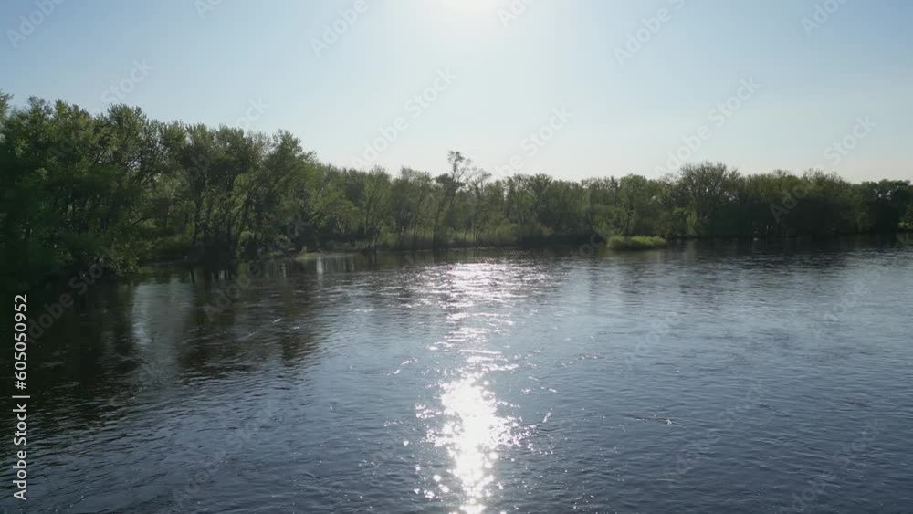Blue River Surrounded By Green Forest and Trees Along Shoreline with Flowing Water and Reflections Blue River Surrounded By Green Forest and Trees Along Shoreline with Flowing Water and Reflections