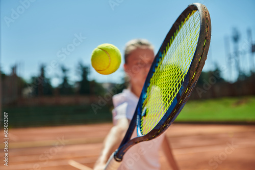 Close up photo of a young girl showing professional tennis skills in a competitive match on a sunny day, surrounded by the modern aesthetics of a tennis court.