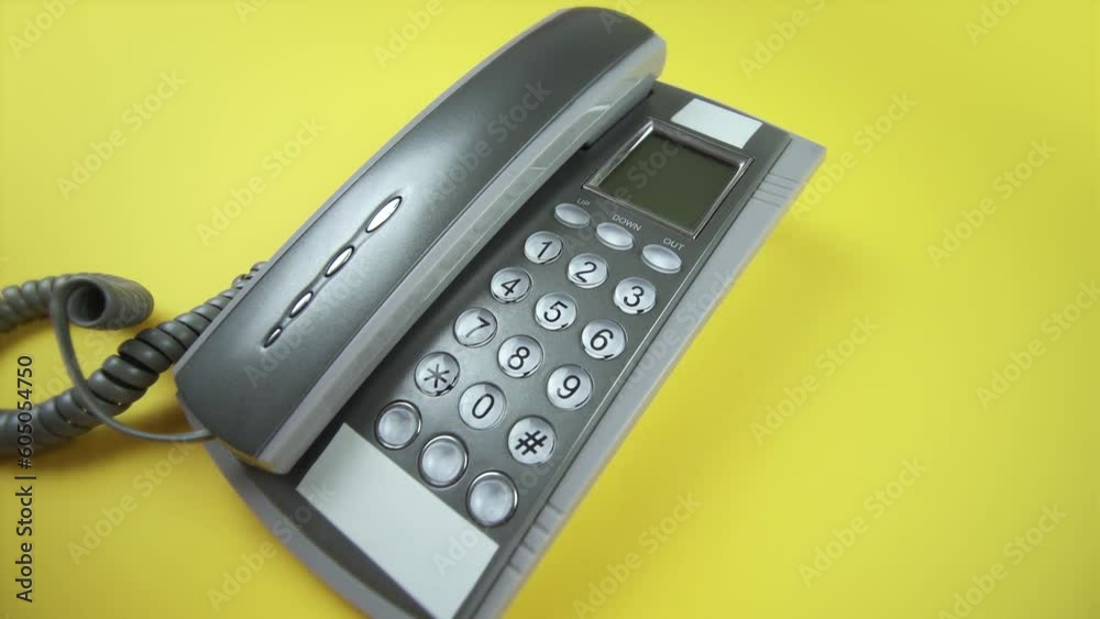 person puts handset on grey corded phone on yellow closeup person puts handset on grey corded phone on yellow closeup