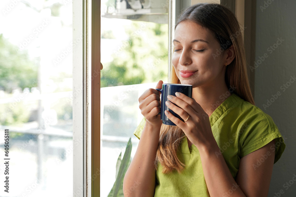 Relaxed beautiful young woman smelling her herbal tea at home in the morning Relaxed beautiful young woman smelling her herbal tea at home in the morning