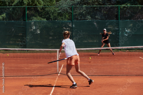 Young girls in a lively tennis match on a sunny day, demonstrating their skills and enthusiasm on a modern tennis court.