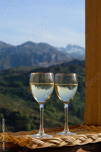 Glasses of swiss or savoy dry white wine with Alpine mountains peaks on background in sunny day