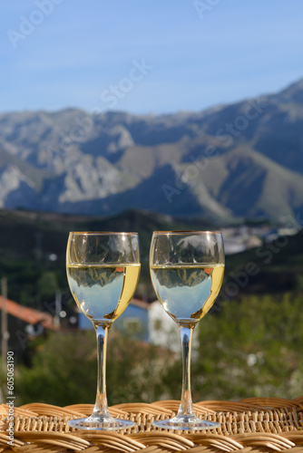 Glasses of swiss or savoy dry white wine with Alpine mountains peaks on background in sunny day