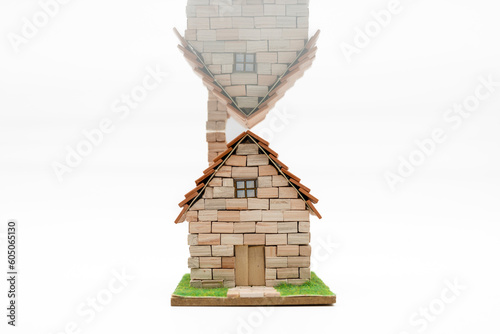 Casa en miniatura hecha de pequeños bloques de piedra, reflejada por el tejado