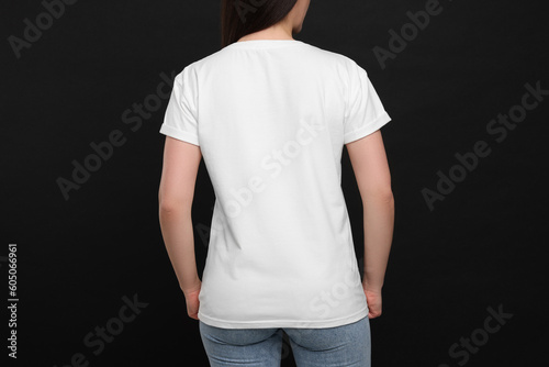 Woman wearing white t-shirt on black background, back view