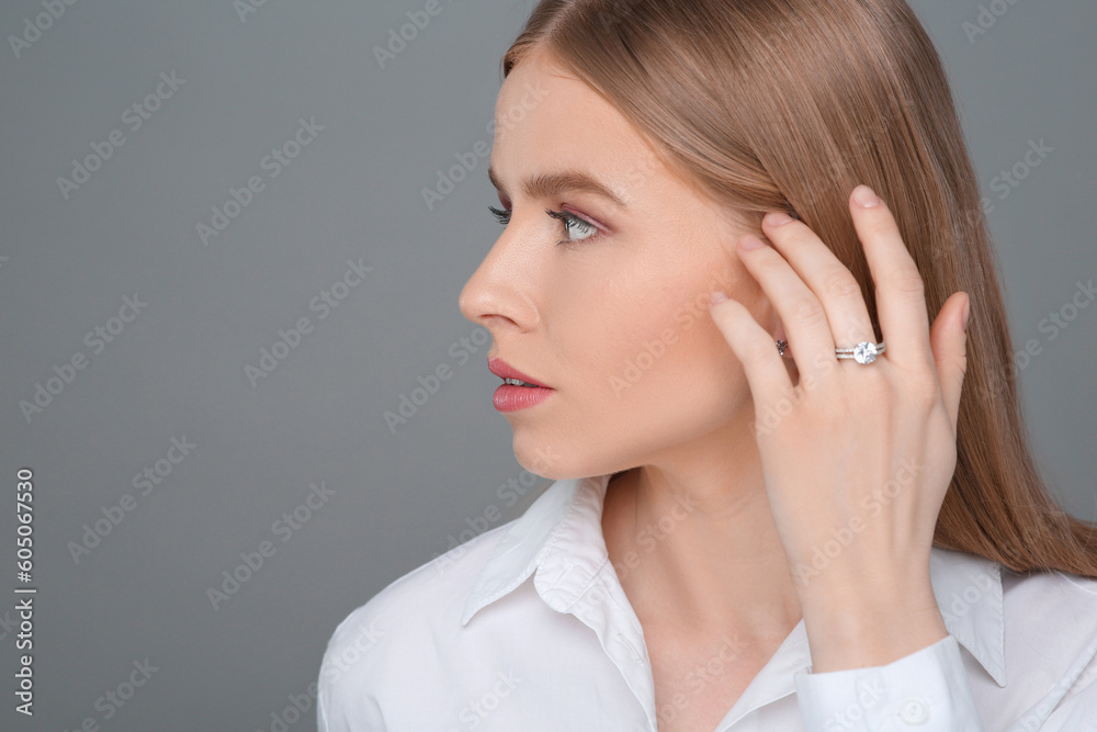 Beautiful young woman with elegant ring on gray background, space for text Beautiful young woman with elegant ring on gray background, space for text