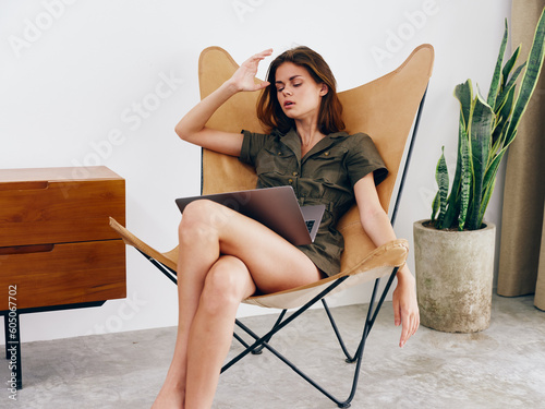 Fototapeta Female freelancer sitting in a chair with a laptop work at home sadness dissatisfaction tiredness, modern stylish interior Scandinavian lifestyle, copy space