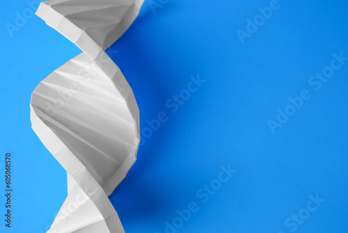 Paper model of DNA molecular chain on light blue background, above view. Space for text