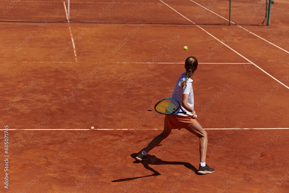 A young girl showing professional tennis skills in a competitive match on a sunny day, surrounded by the modern aesthetics of a tennis court.